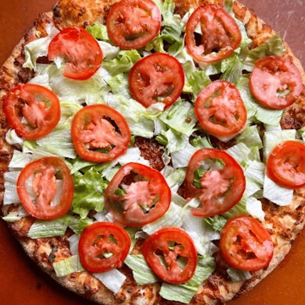 Detroit Pizza's pizza topped with fresh lettuce and sliced tomatoes, ready to be served.